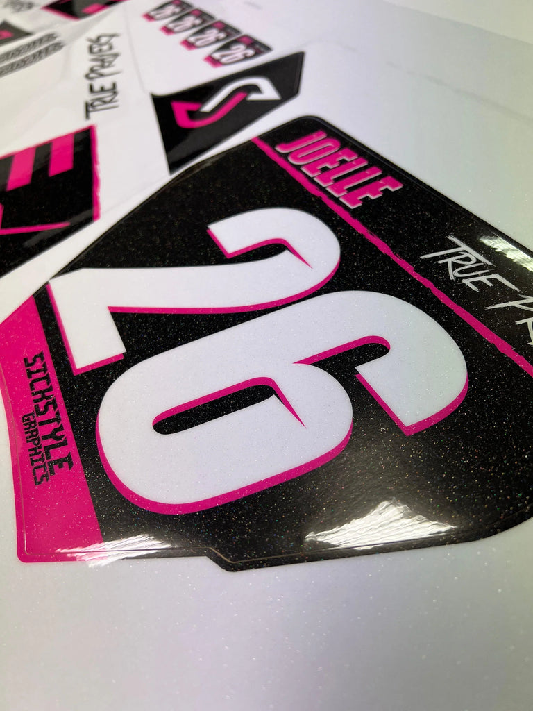 Glitzerndes, schwarzes Bike Dekor mit pinken Akzenten und weißer Nummer 26.