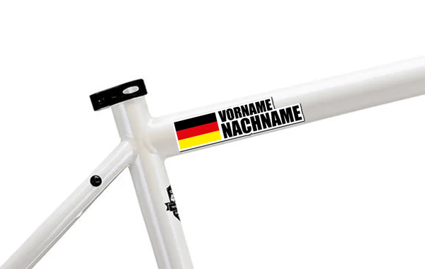 Personalisierbarer Namen-Aufkleber mit deutscher Flagge und schwarzem Text “VORNAME NACHNAME” auf weißem Fahrradrahmen.