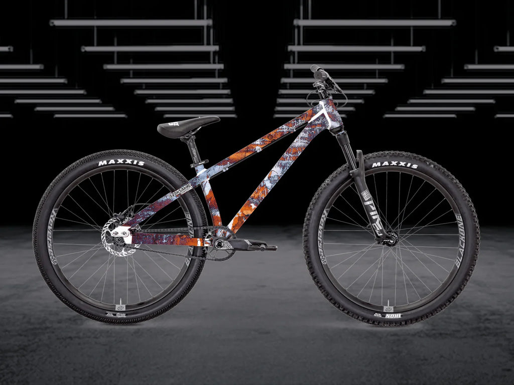 The Bruce 2 dirt jump bike med unik rostmönstrad ram, svarta komponenter och Maxxis-däck.