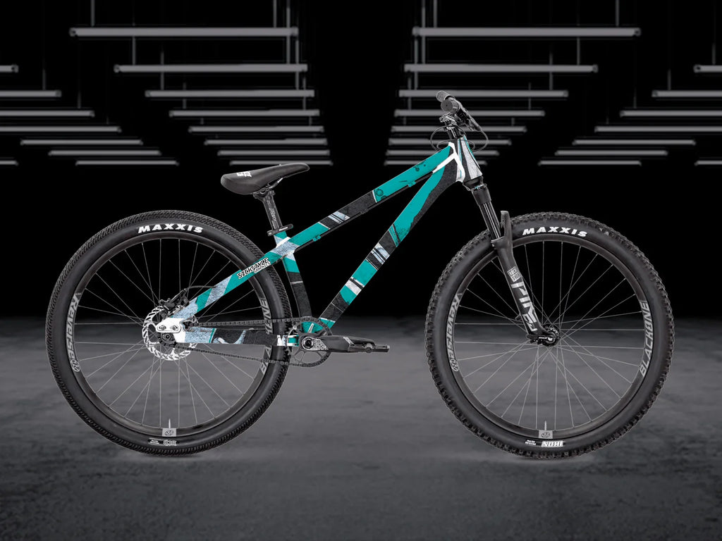 The Bruce 2 Frameguard dirt jump bike med teal, svart och vit geometrisk “Stripo”-design.